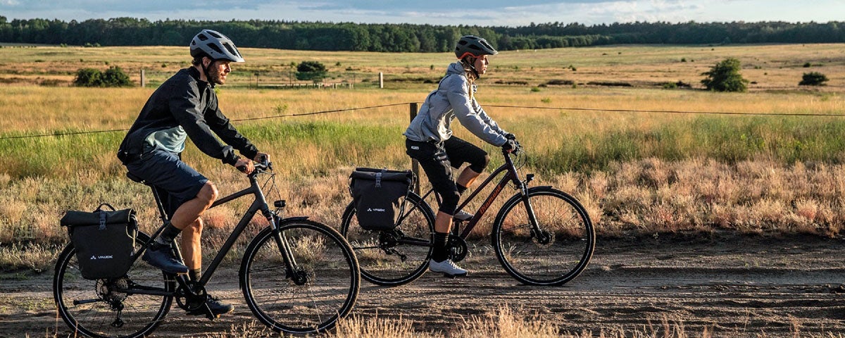 A man and woman cycling along a trackway in an open field