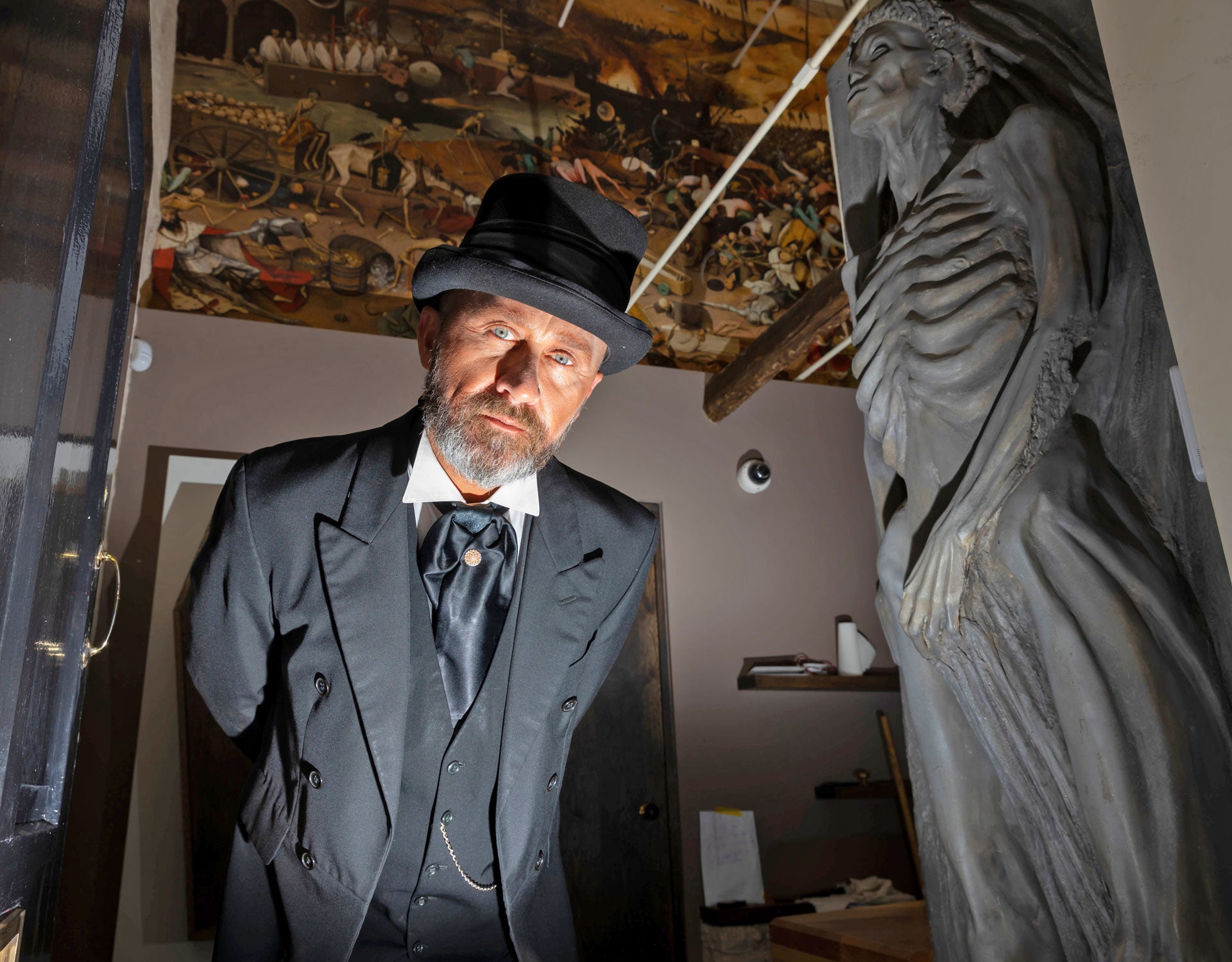 Waterford Treasures - Irish Wake Museum guide in a top hat next to a stone skeleton carving