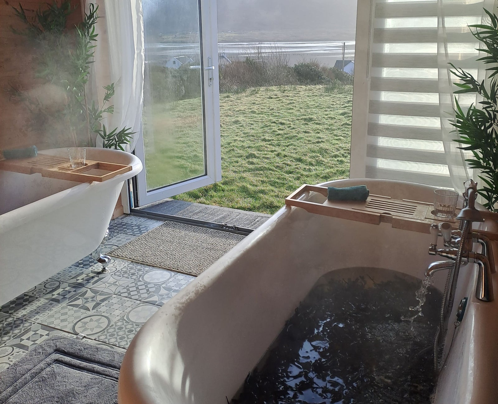A room with two baths with seaweed and doors open to sea view