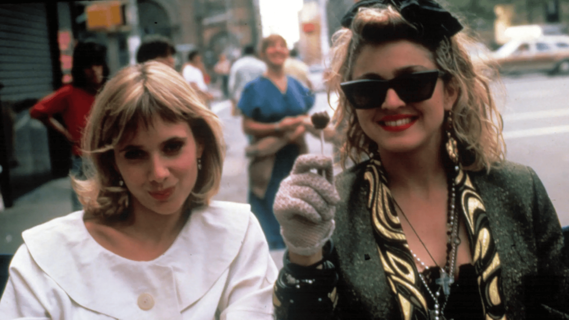 Two smiling women. One is dressed simply, the other boldly.