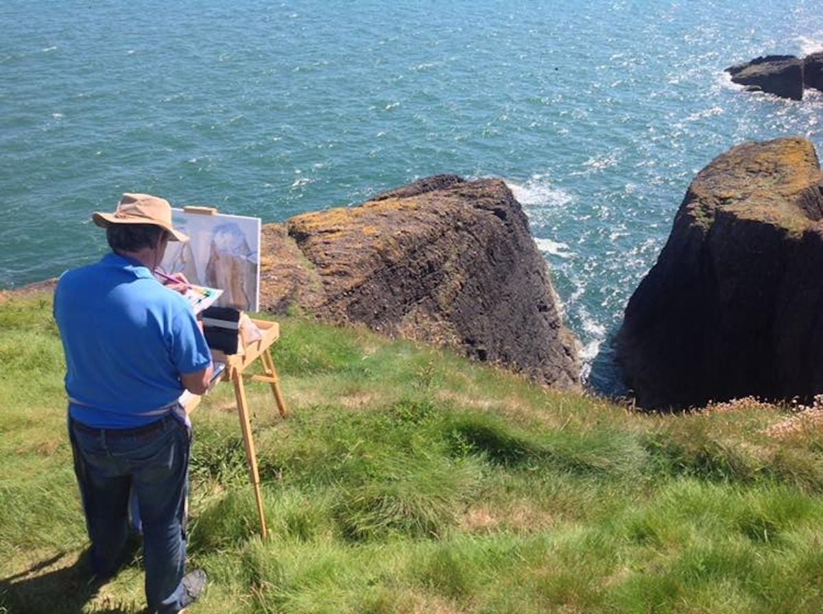 An artist painting on a cliff top