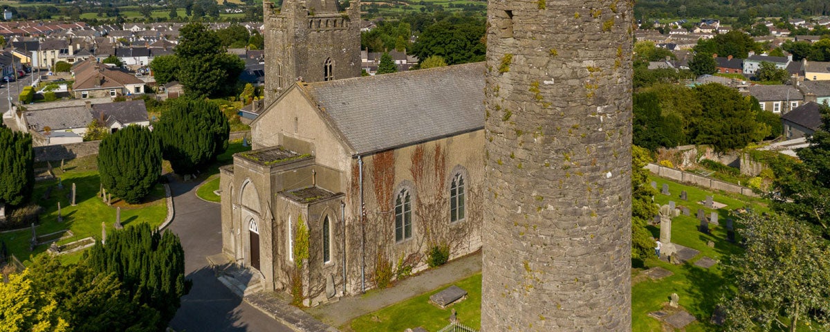 A church beside a round tower overlooking a town