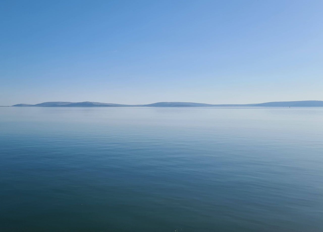 Calm blue sea with distant low hills on the horizon
