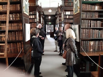 Visitors gather among the towering oak bookcases of Marsh's Library, Dublin's oldest public library, filled with centuries-old volumes — a fitting stop for tracing the roots of Irish gothic literature.
