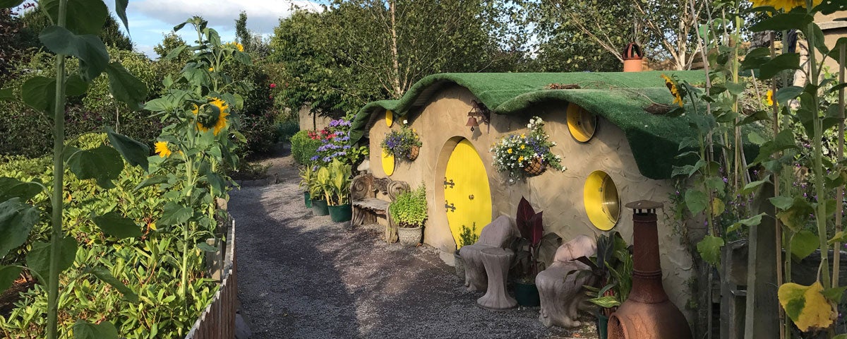A row of round fairy houses surrounded by shrubs and flowers at Glenview Gardens in County Cork