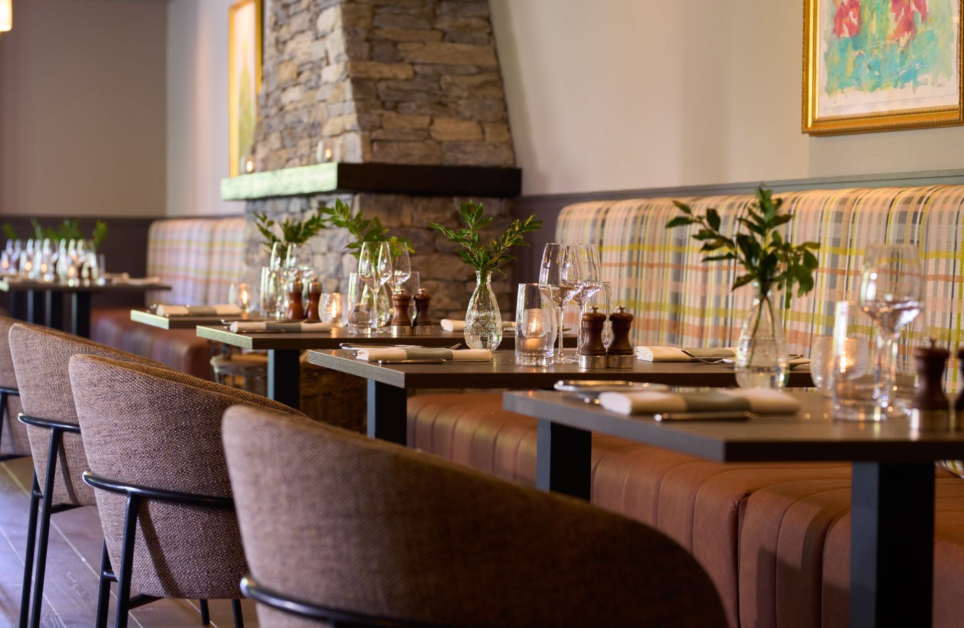 Four tables set for dinner for two beside a stone chimney breast