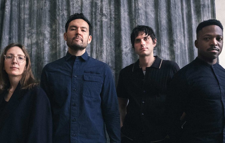 4 serious looking people in a line, dressed in dark clothes.