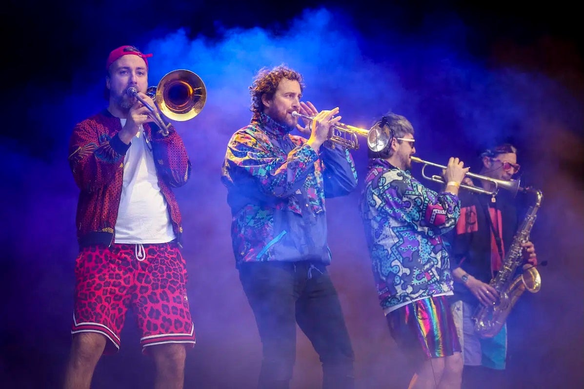 4 musicians playing brass instruments on a hazy stage