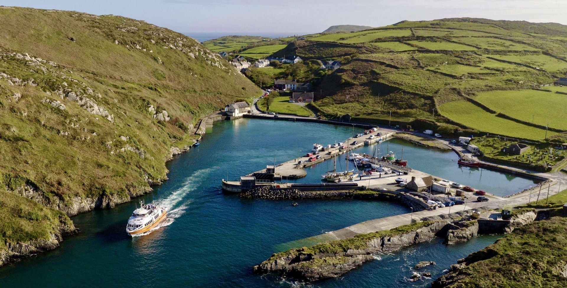 An aerial view of the pier at Cape Clear Island with a ferry sailing out