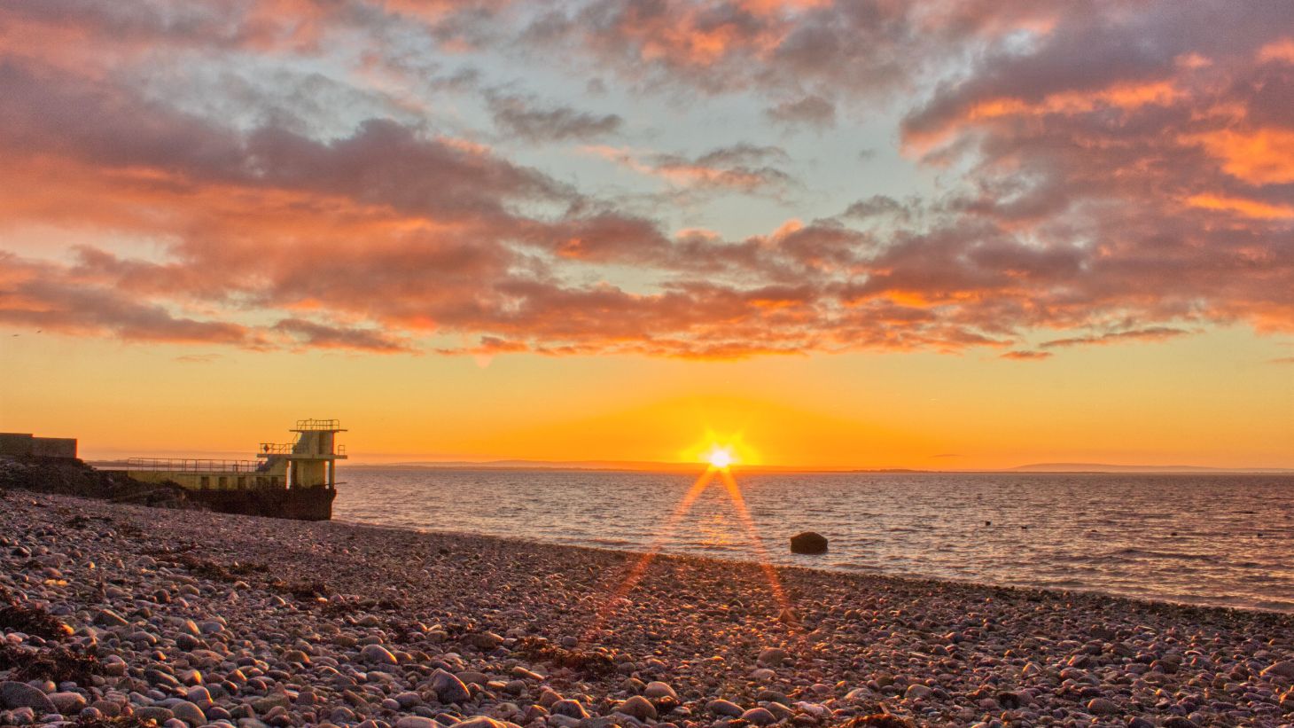 The sun over the sea at Salthill with Blackrock Diving Tower in the distance