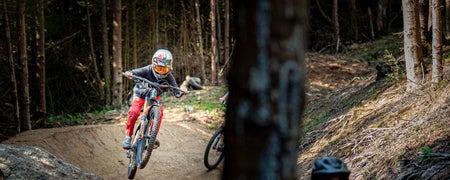 Two kids on bikes speeding down a forest track at Glencullen Adventure Park