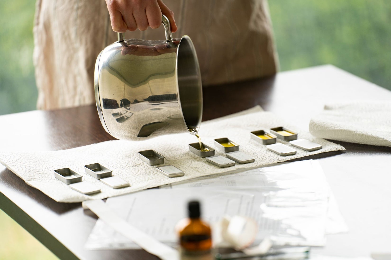 A person pouring liquid into small moulds
