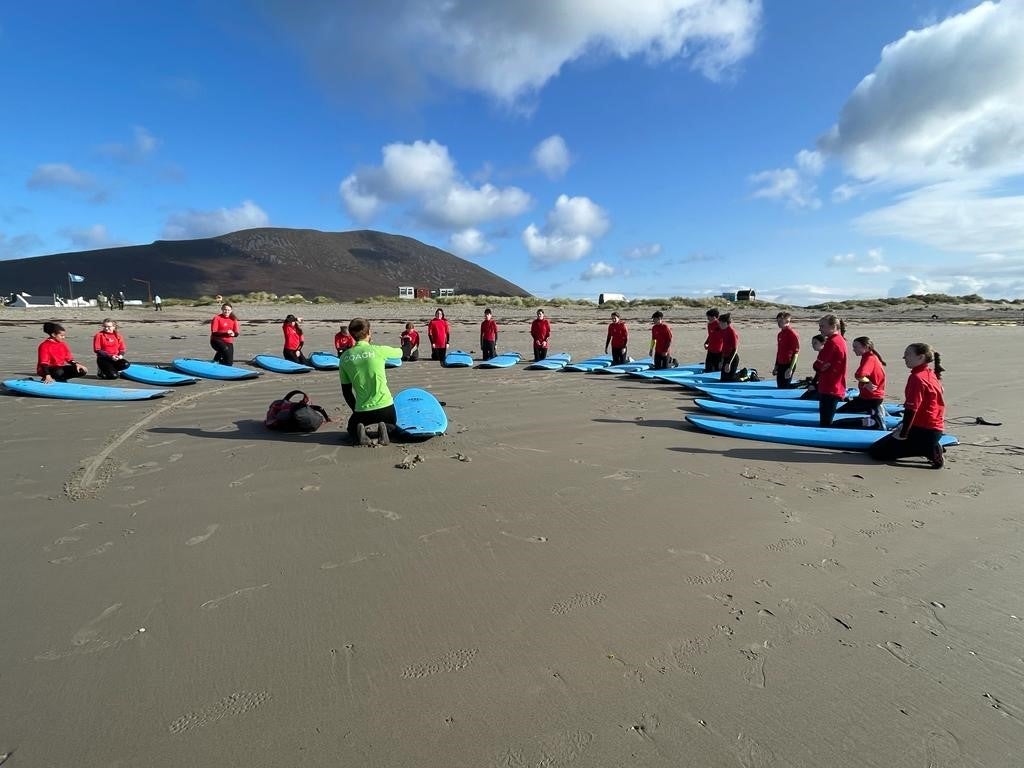 A group of girls with surf board on a beach in a semi circle