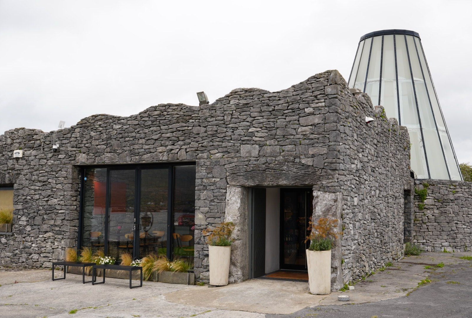 Stone built exterior of a building with large glass dome feature in the background