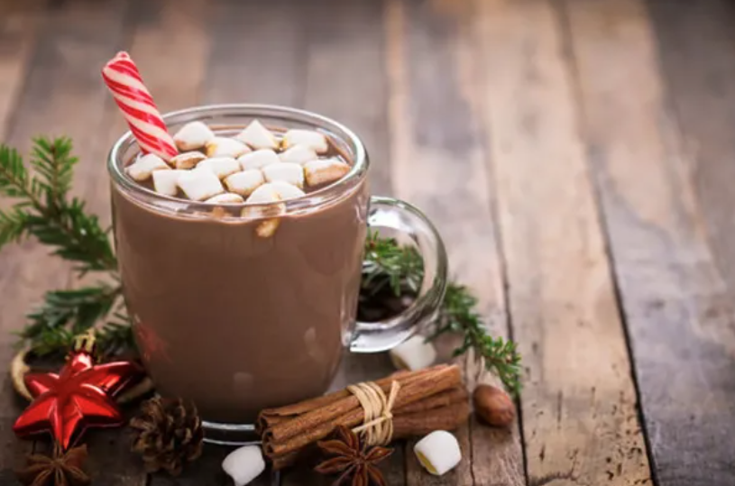 A clear mug of hot chocolate with small marshmallows on the surface