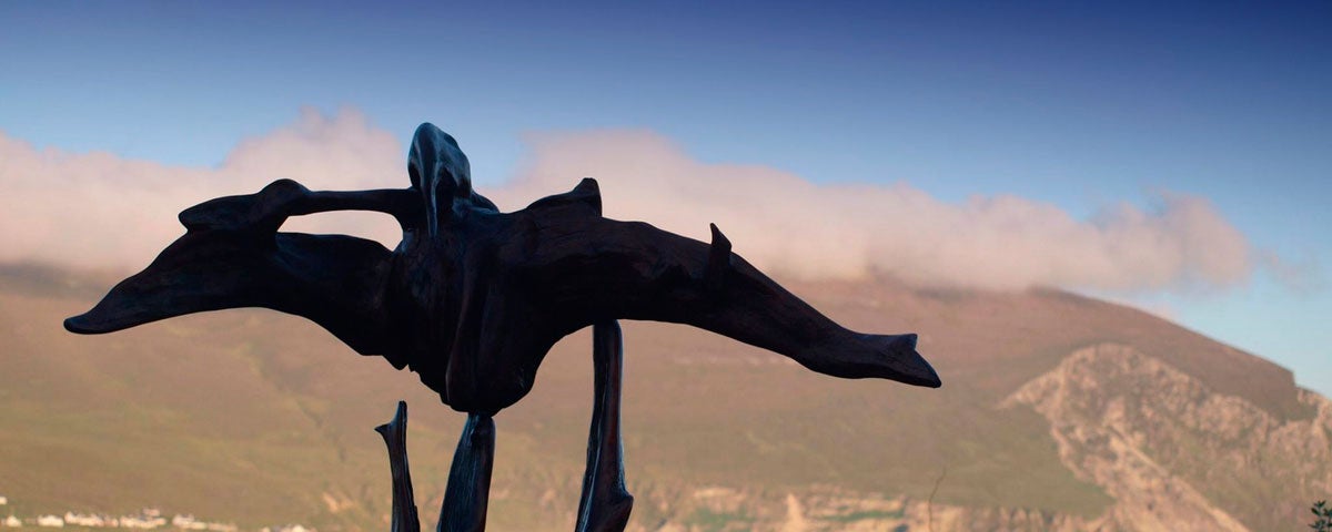 A sculpture in bog oak with hills of Achill in background giving the impression of a bird flying