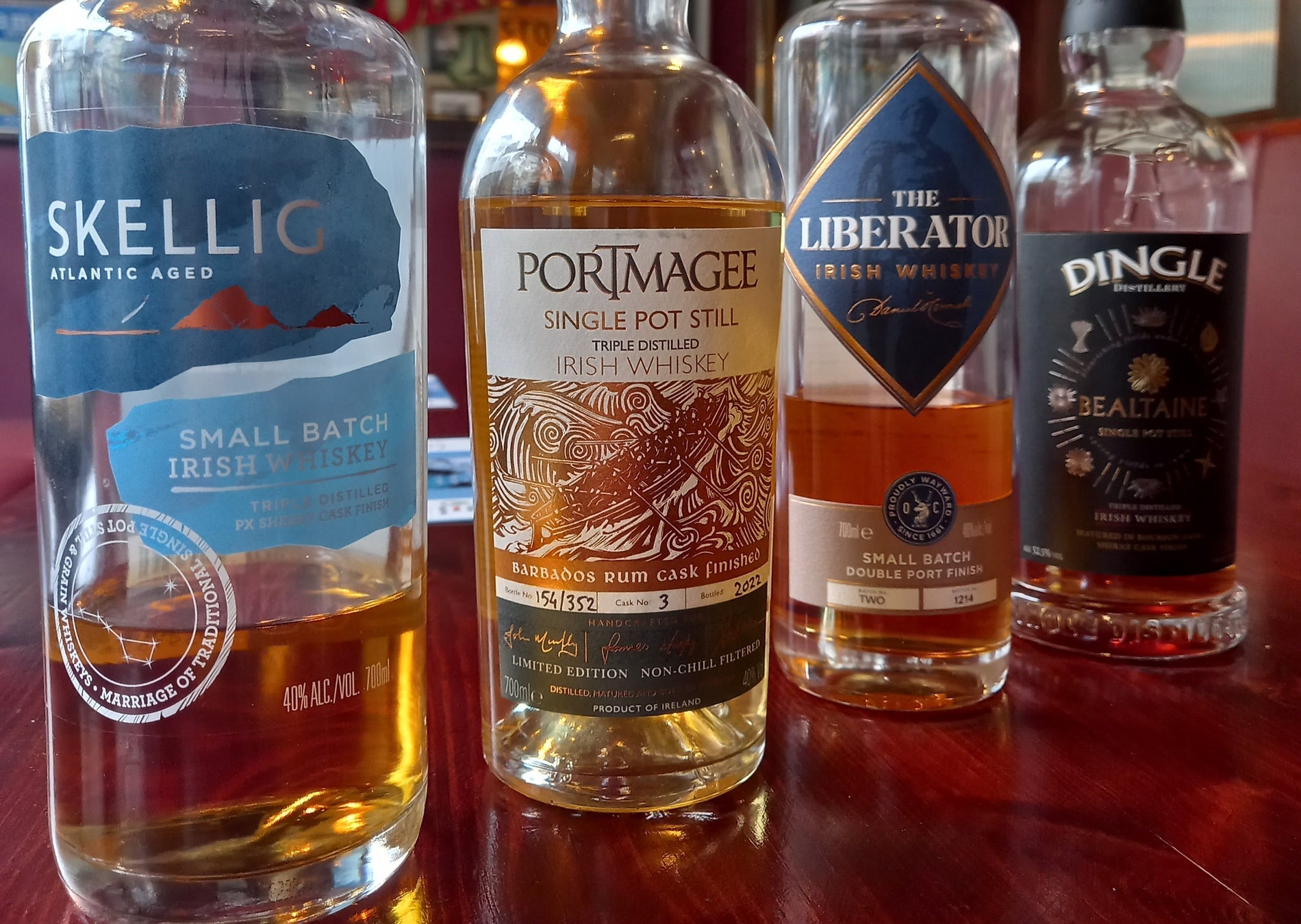 Four whiskey bottles on a wooden counter