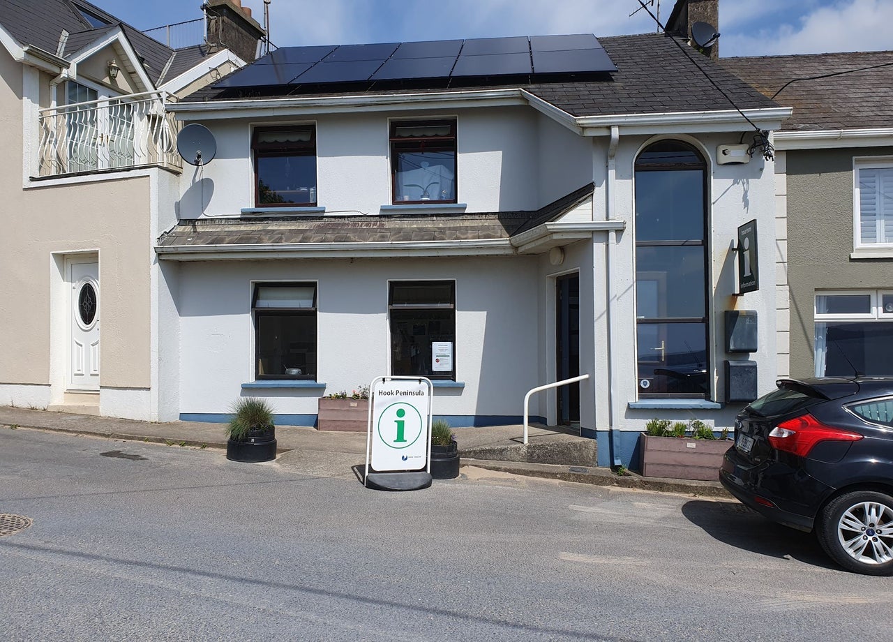 Exterior of a two storey building on a street with a tourist information sign outside