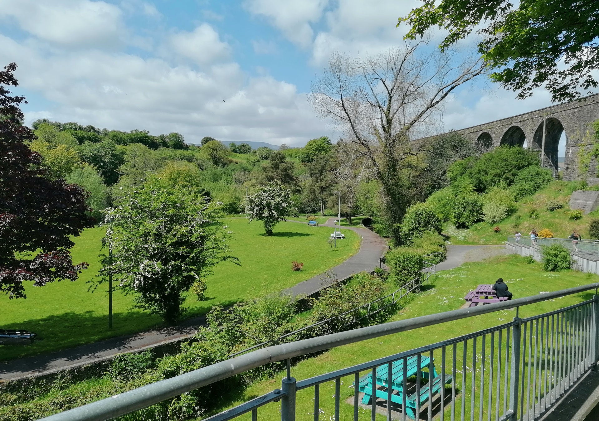 StepsBackThruTime Guided Walking Tour Experiences view of a park area overlooked by a grey stone bridge with arches