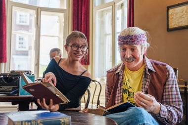 A lady poses with an open book beside a wax figure of Pat Ingoldsby