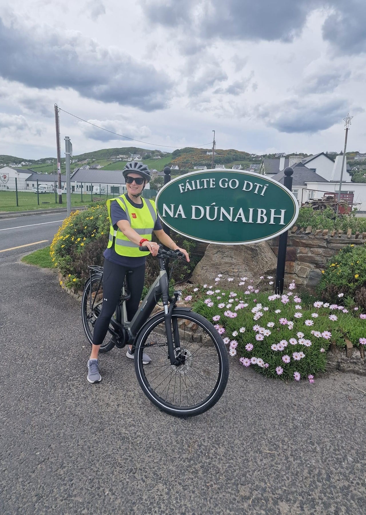 A lady on an ebike stopped at a village sign