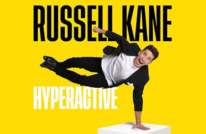 A man is horizontal balancing on his left hand on a white box with shouting expression on face, against bright yellow background with black or white text.