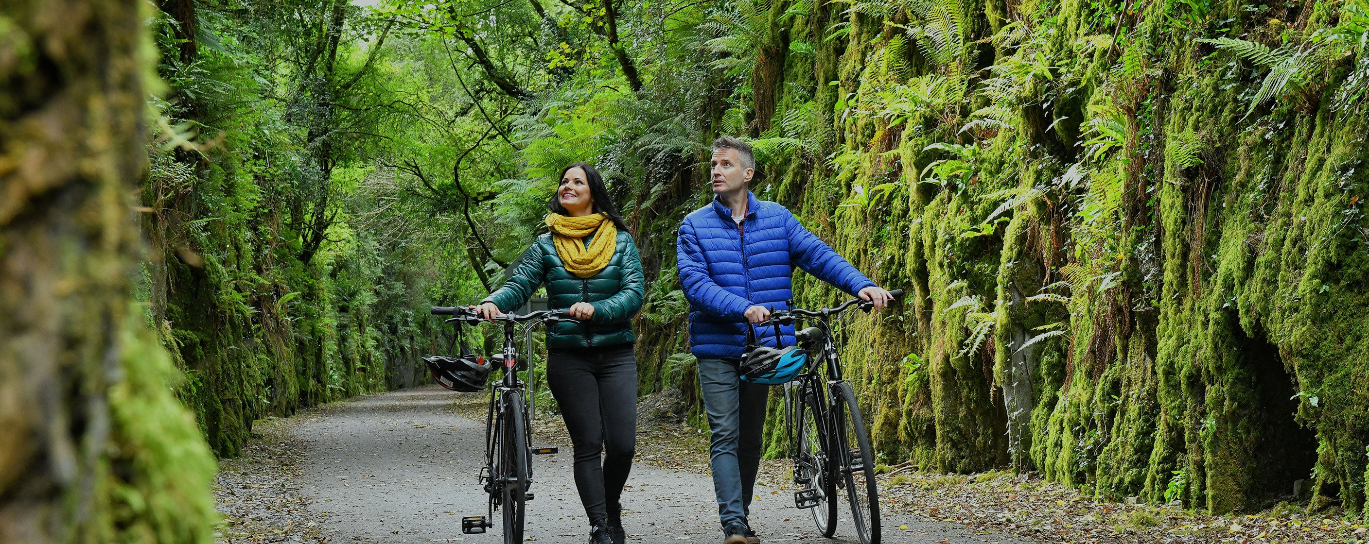 Man and woman walking their bikes through the Waterford Greenway 