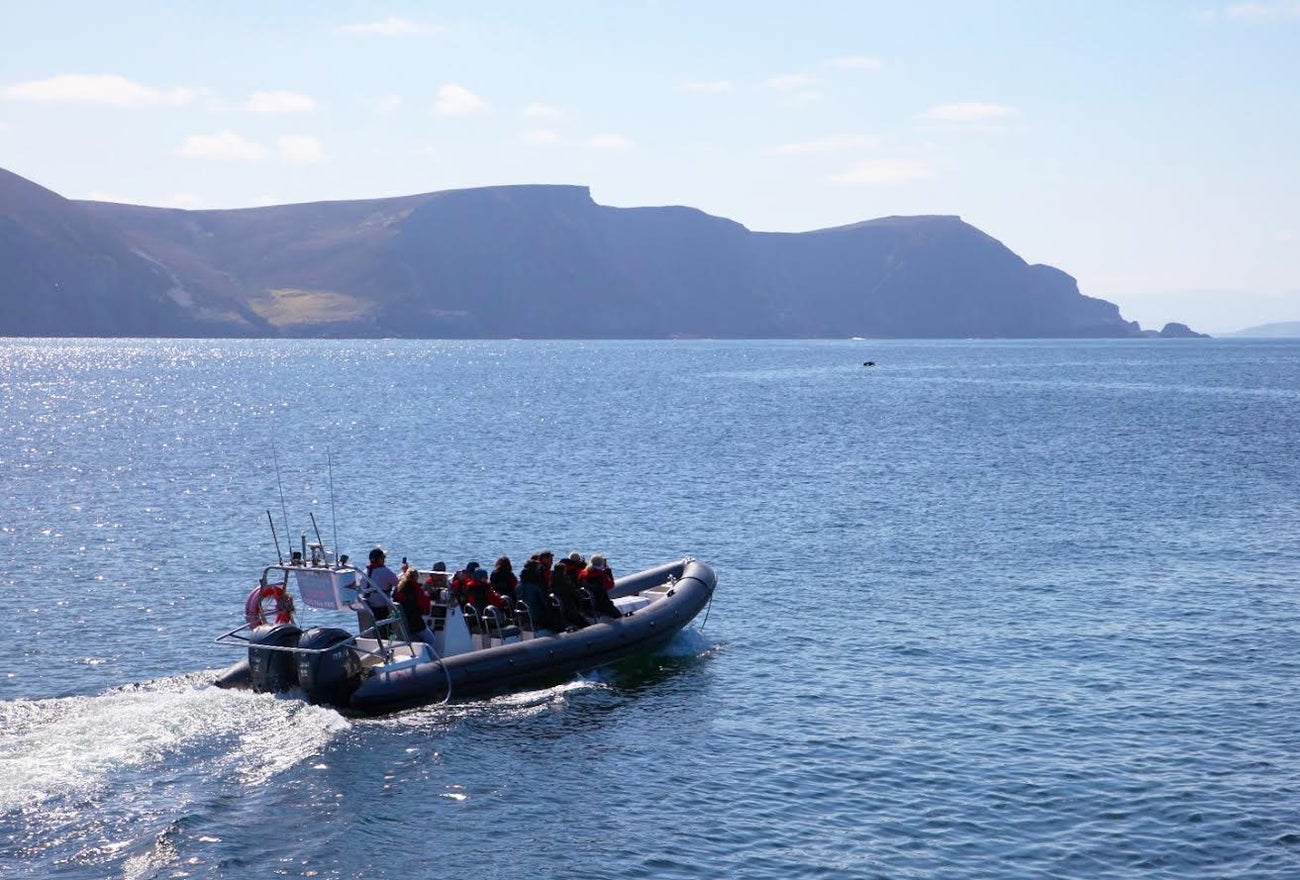 Group on a RIB at sea with mountains in the background