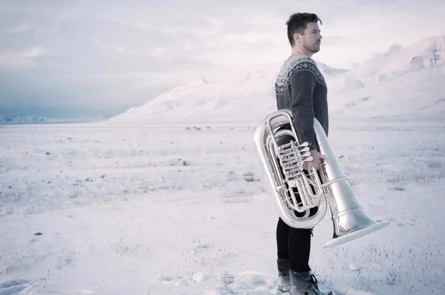 A man with a tuba is standing on a beach