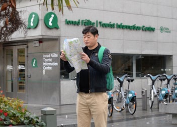 A tourist standing outside Dublin Tourist Information Centre Barnardo Square reading a map