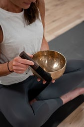 A person in a yoga pose holding a sound bowl