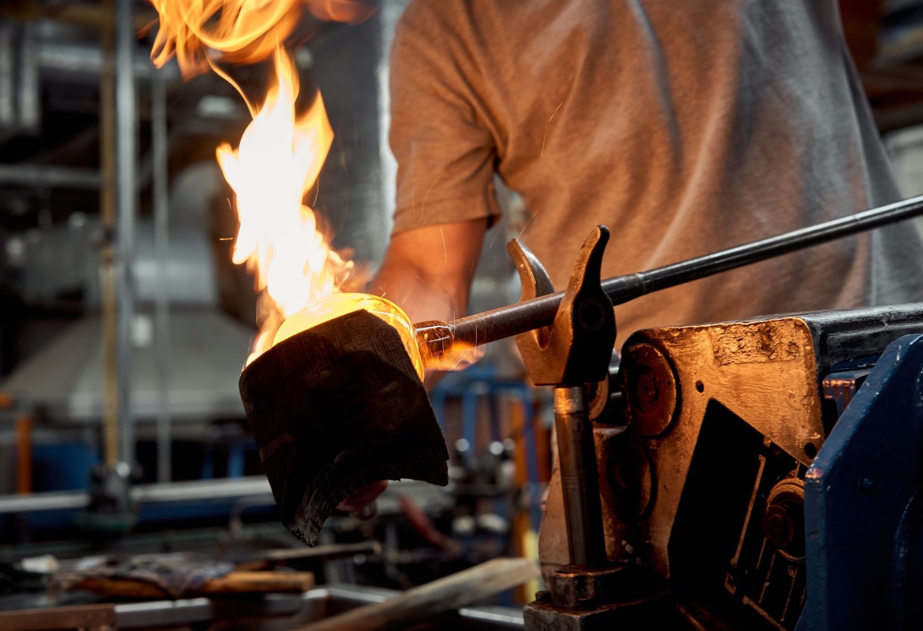 Person holding a piece of crystal on an iron poker over a large flame