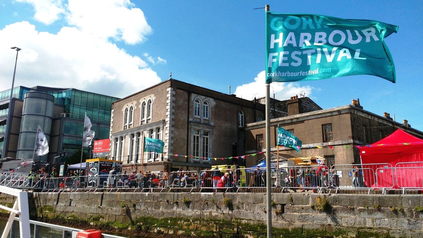Buildings along side a quay on a sunny day with a blue flag flying