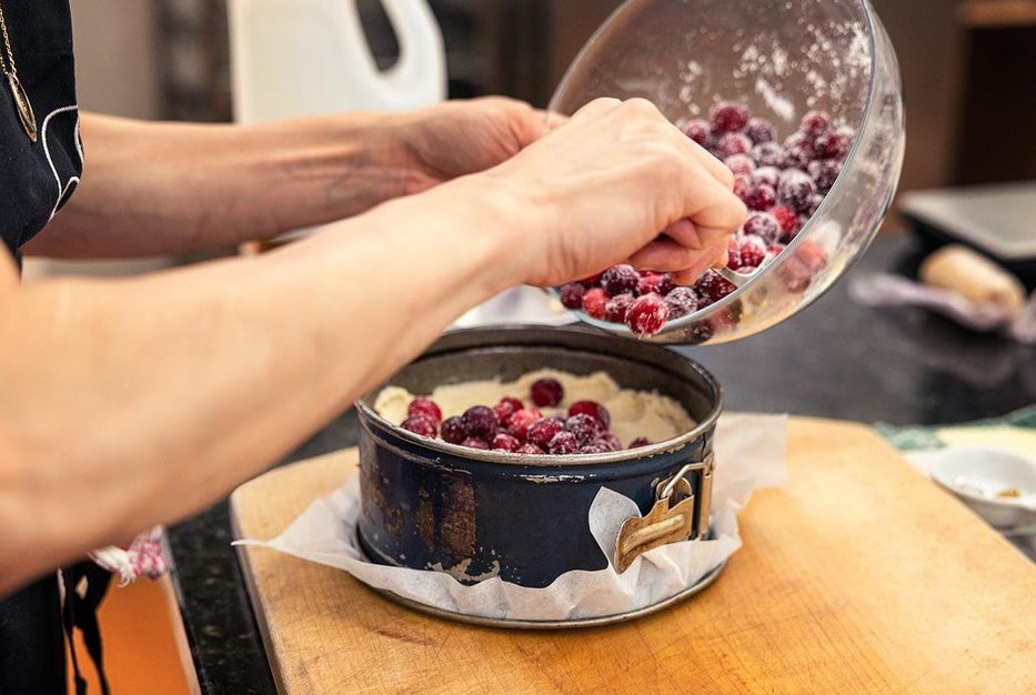 Dublin Cookery School, Festive Supper Club - a pair of hands tipping red berries into a cake tin.