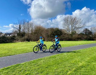 Two people out cycling wearing blue high visibility waistcoat and blue bike helmets