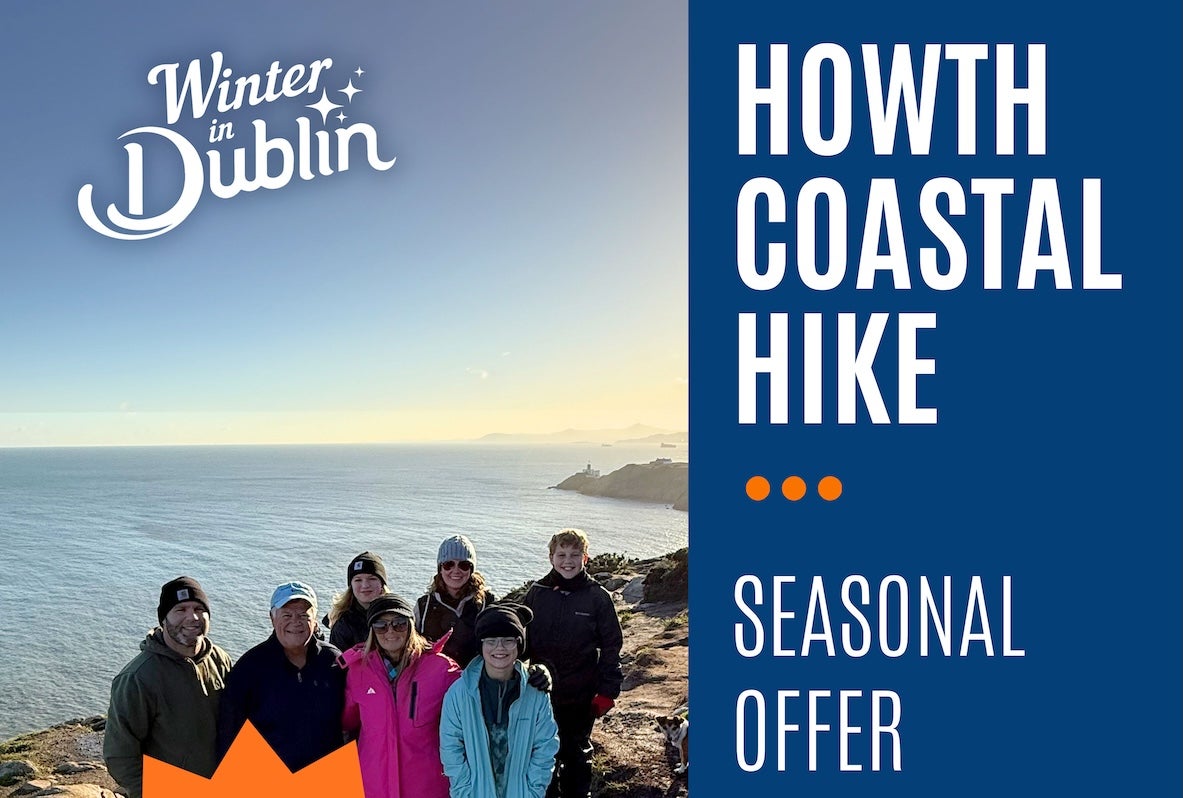 A group of smiling people outdoors with the sea in the background.
