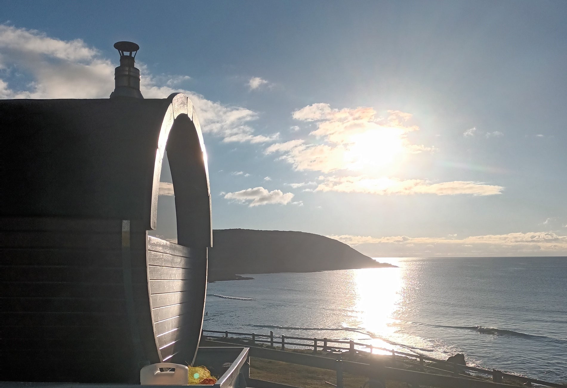 Mobile sauna by a beach with the sun setting over the sea