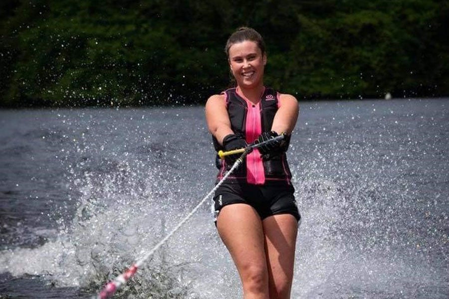 A woman smiling into the camera as she water skis