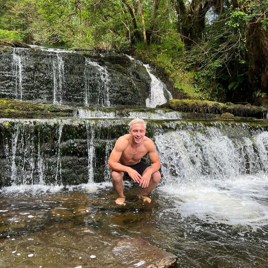 Man kneeling in the water near the bottom of Fowley's Falls.