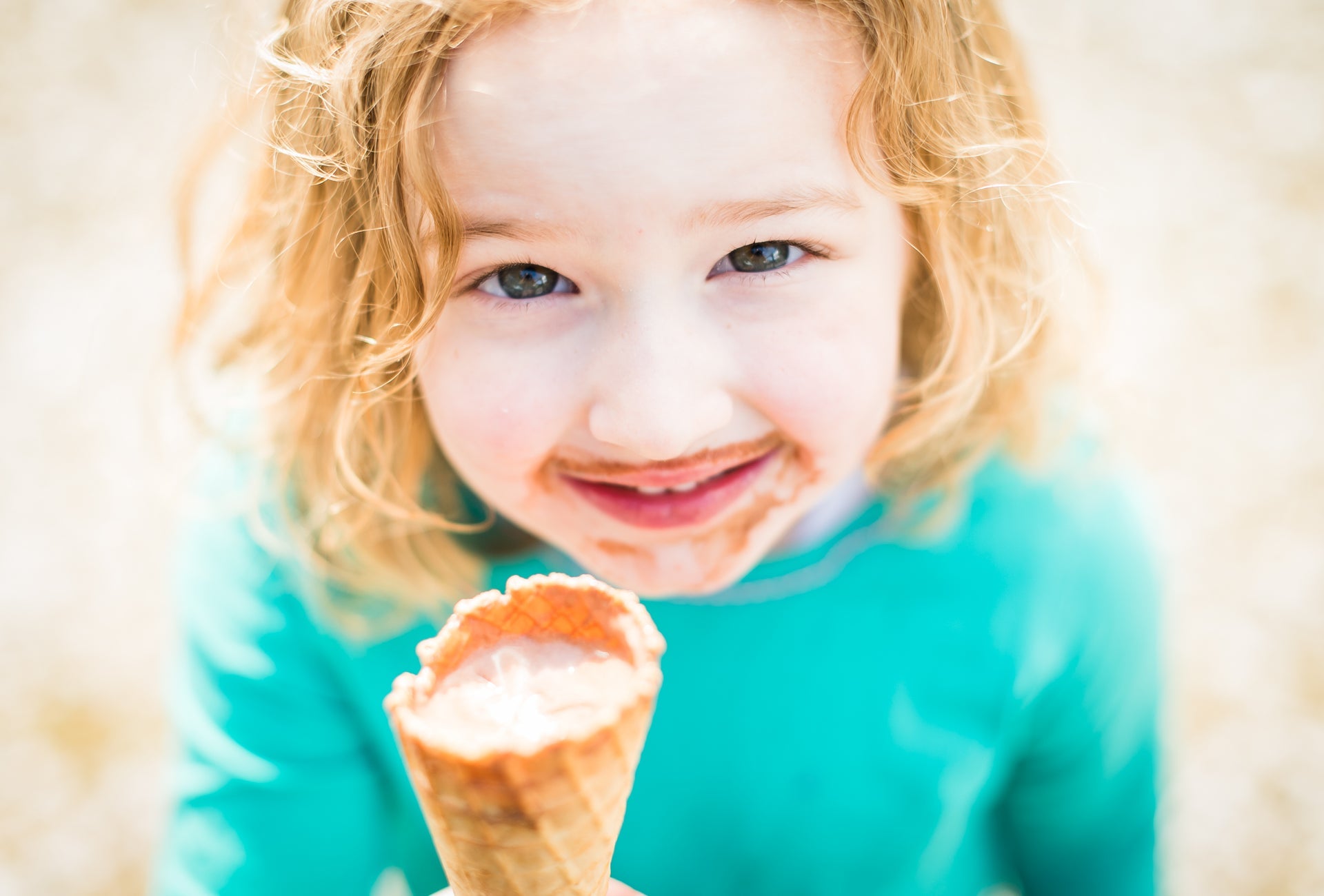 A smiling young girl enjoys ice cream from a cone