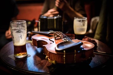 Two nearly empty pint glasses on a pub table with a fiddle in the middle