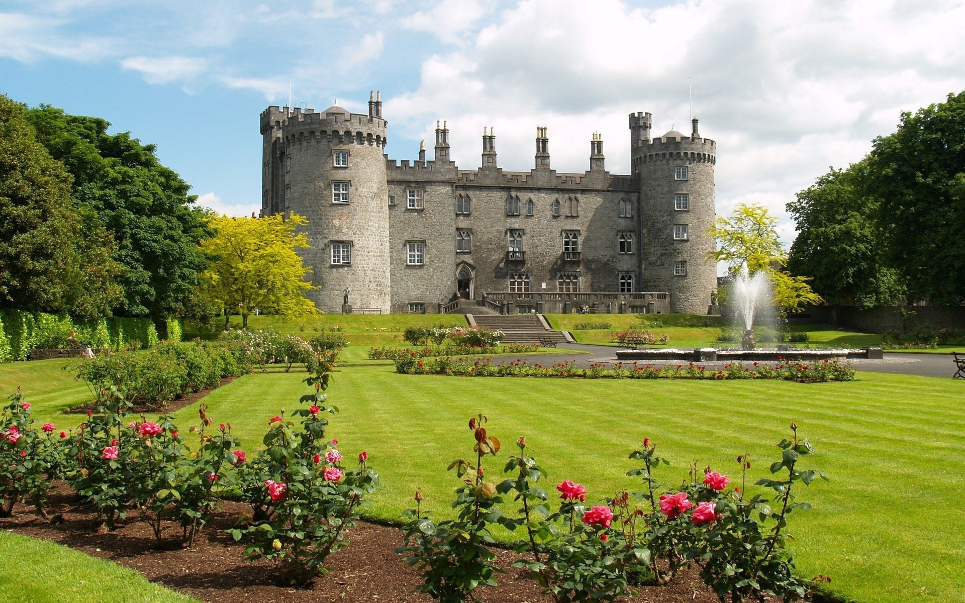 A view of Kilkenny Castle with a border of red and pink roses in foreground