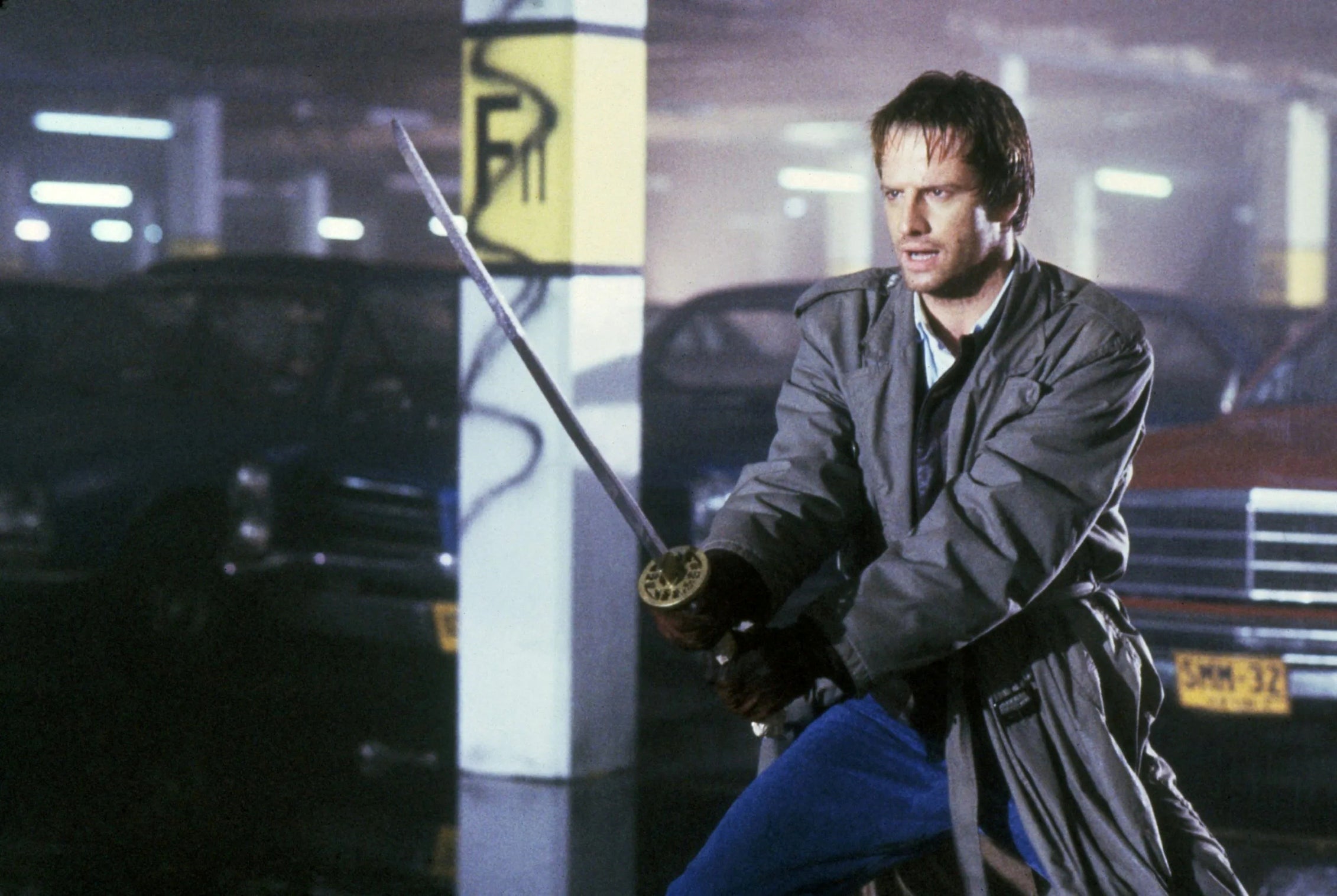 A man wielding a katana in a parking lot.