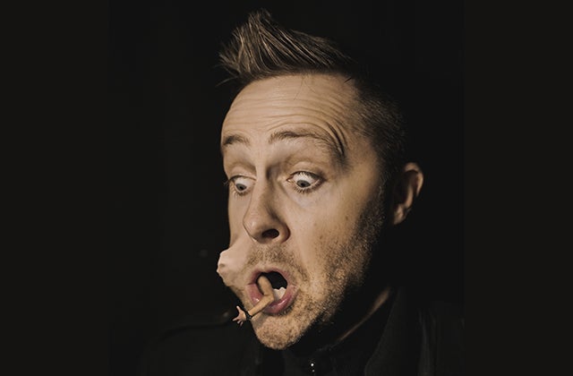 The legendary Keith Barry brings his mind blowing show, Mind Games, back to Wexford Spiegeltent Festival 2024. Head view of man looking shocked with tiny person in his mouth pushing out his cheek.