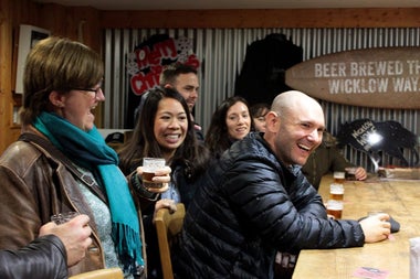 Group sitting at a wooden beer tasting table with glasses in front of them