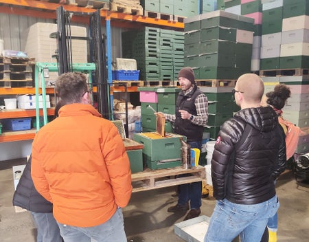Olly's Farm group watching a guide showing honeycomb from a beehive