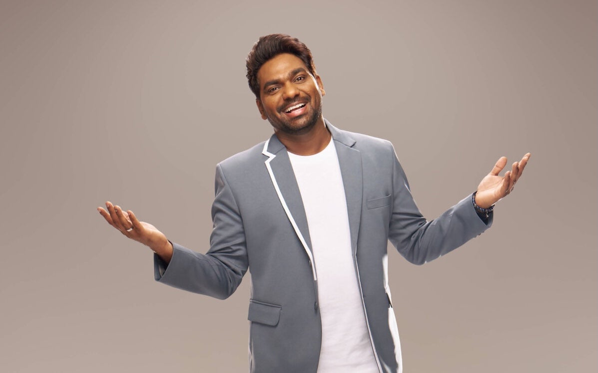 Indian global comedian Zakir Khan - a laughing man with arms open wide.