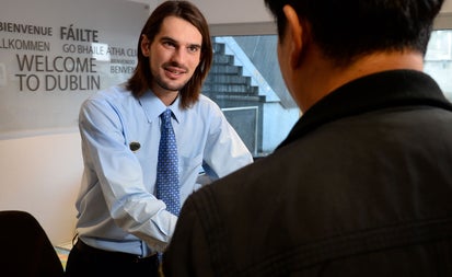 A member of staff at the desk helping a visitor with information at Dublin Tourist Information Centre Barnardo square