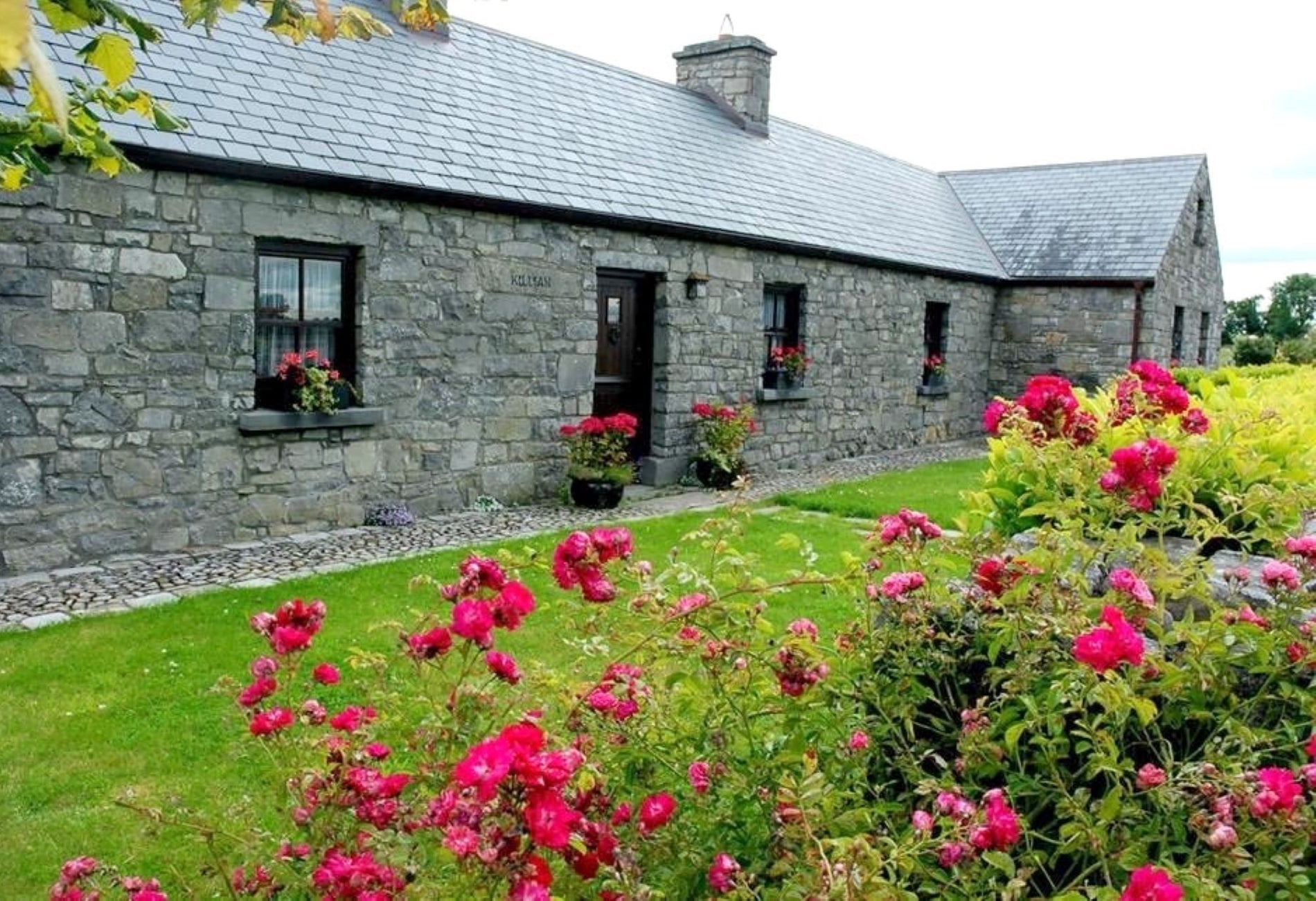 Stone house with pink flower by the door and in the garden in front
