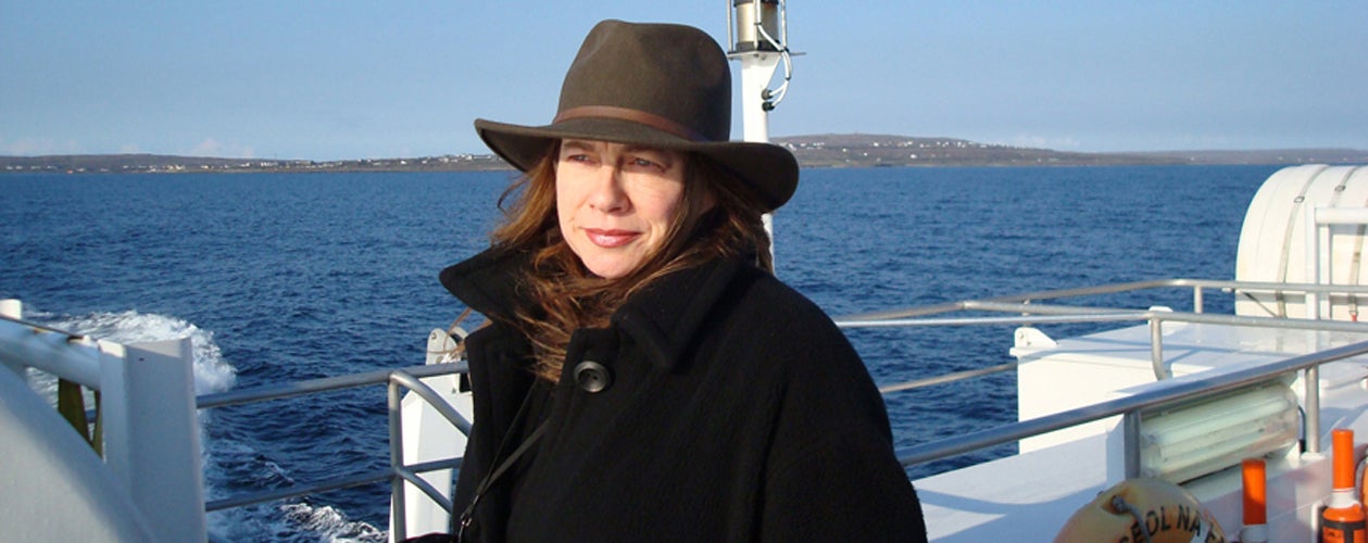 A lady with a hat on a ferry looking out to sea